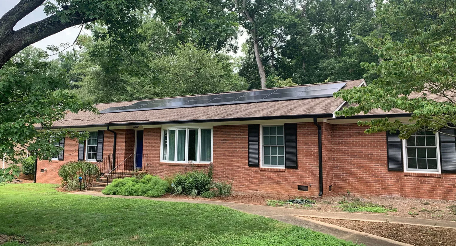 Single story brick home with a solar system on the front of the roof
